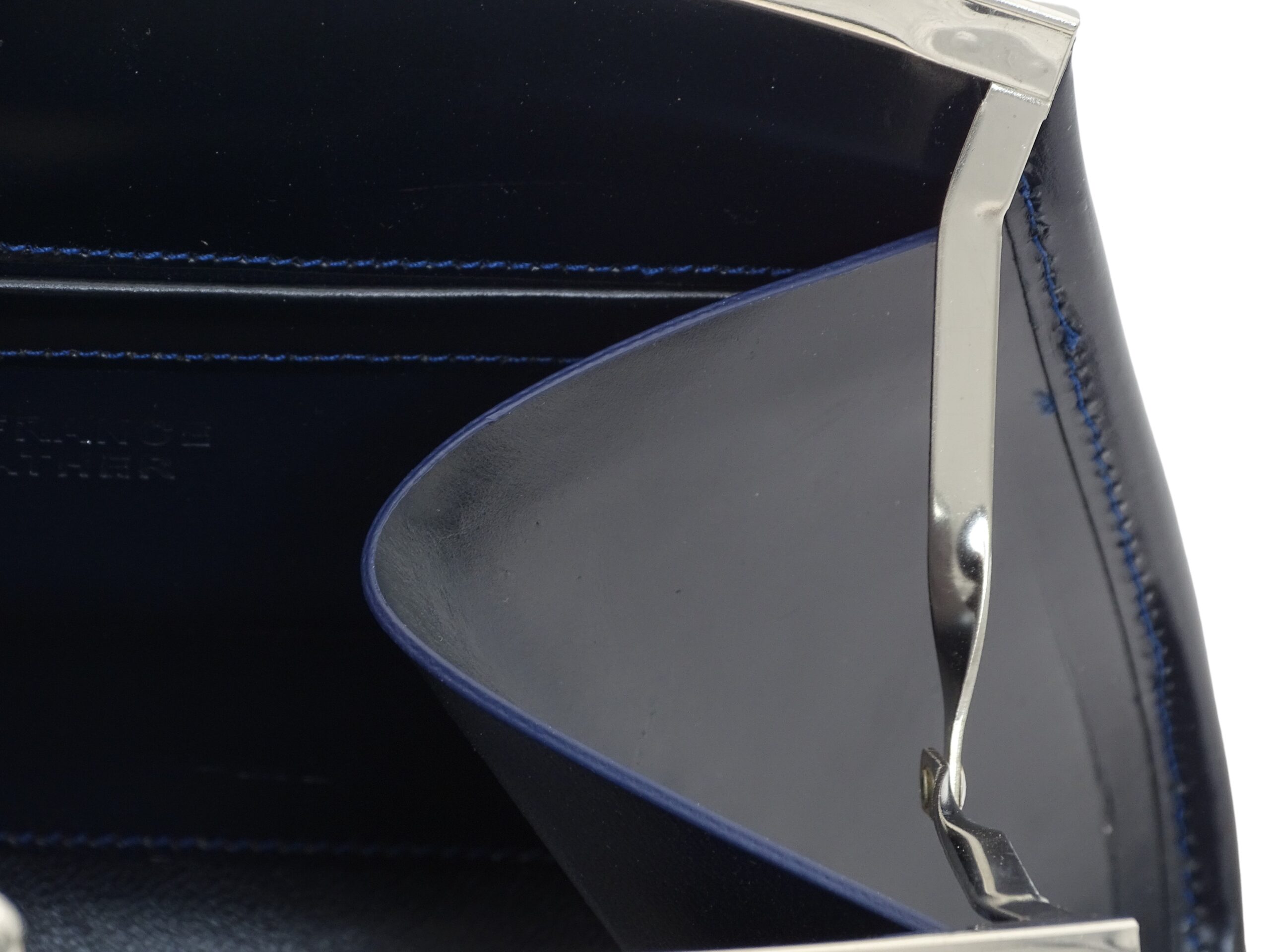 la vue de près du sac marilyne noir met en évidence le magnifique fil de lin bleu utilisé pour coudre les pièces de cuir de haute qualité. La haute maroquinerie française est mise à l'honneur avec ce sac à main de qualité supérieure en cuir véritable.